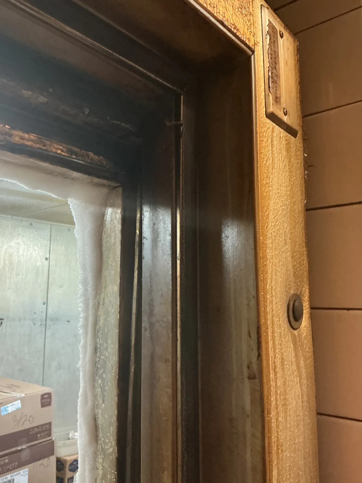 Ice and frost built up along a commercial walk-in freezer door frame from a failed gasket seal