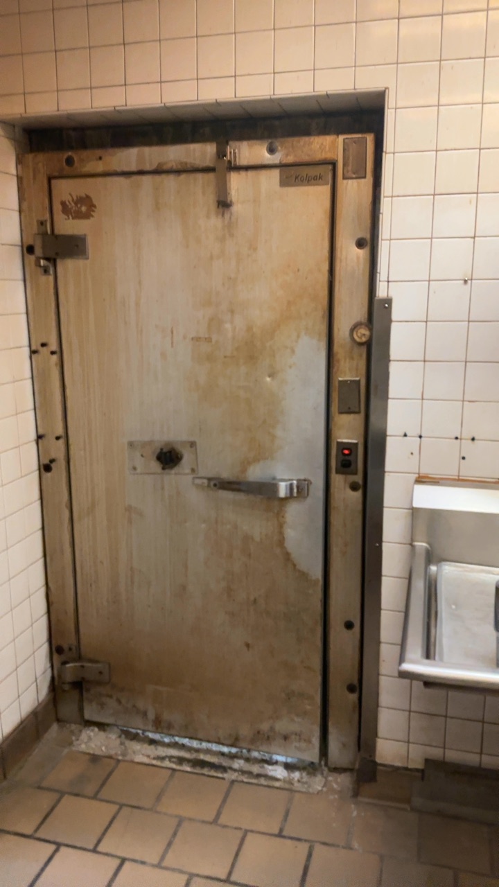 Rusted and stained walk-in cooler door in a commercial kitchen